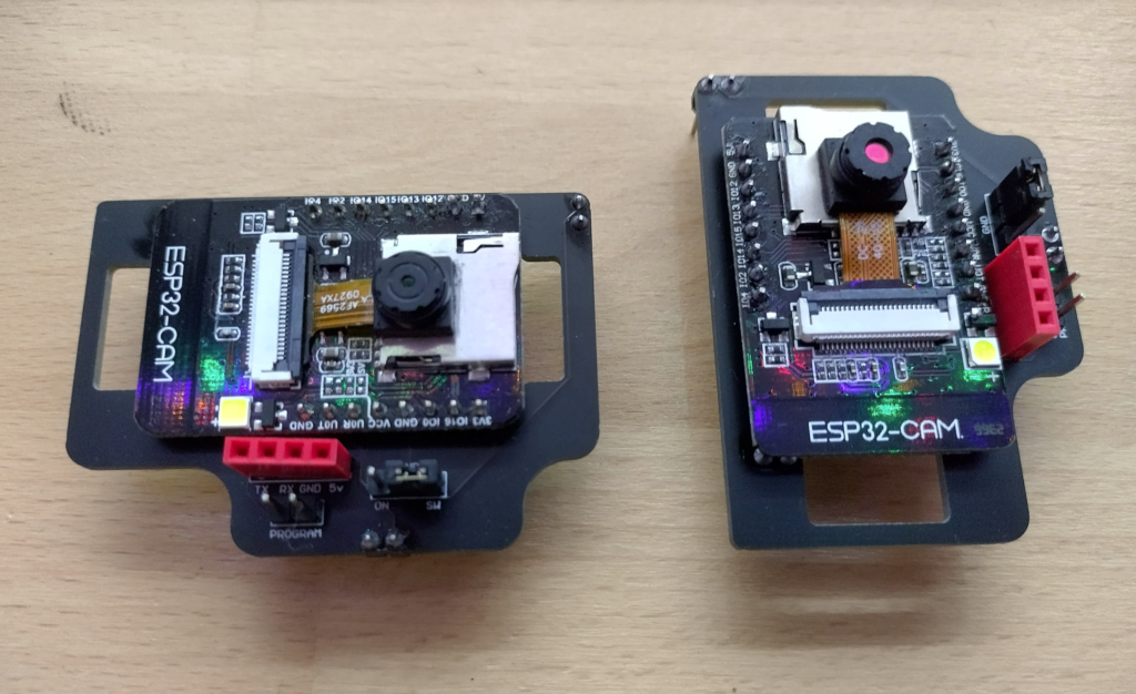 The two different ESP32Cam sensors (ov2640).  Original sensor on the left (with a smaller lens opening, straight pattern on the ribbon cable), newer sensor on the right (larger lens opening, hatch pattern on the ribbon cable).  These are sitting the correct way to get a properly oriented picture according to the sensors.