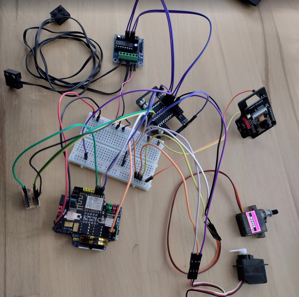 The test robotics circuit, clockwise from top left: L293D motor controller, Combined 74HC595 shift register and ULN2803 darlington array, ESP32cam, MG90s servo, A0090 servo, ResourciBoard with Attiny85's and ESP12F, Shift1 board.