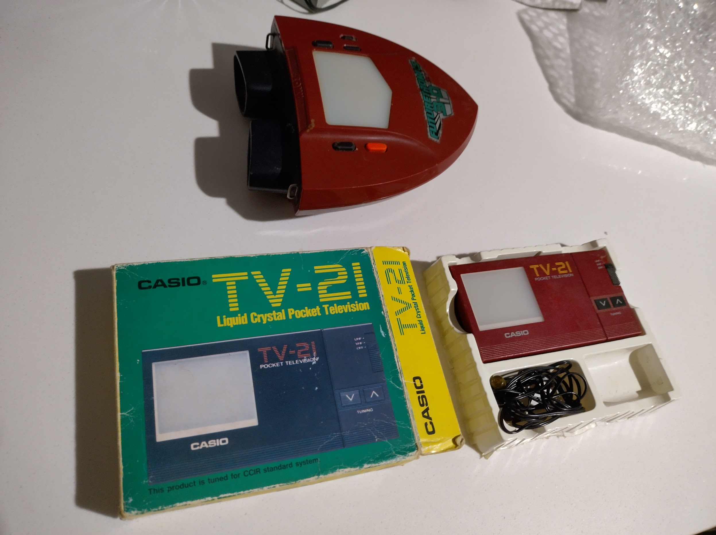 Casio TV-21 Pocket TV shown alongside the original box, and the 3d tron handheld from the 1980s